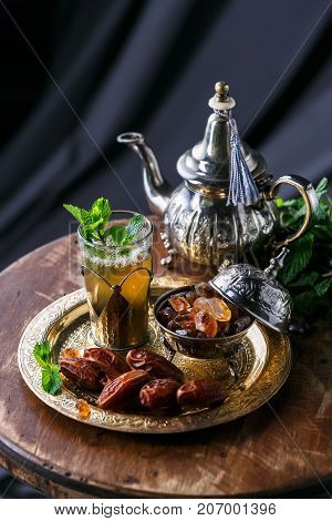 Moroccan tea with mint and sugar in a glass on a dark background.