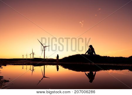 Wind turbines at a wind farm reflected on a water surface at sunset, Crete, Greece