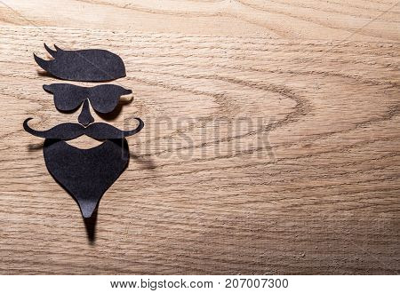 Hipster's definicial facial look cut from paper on the wooden background.