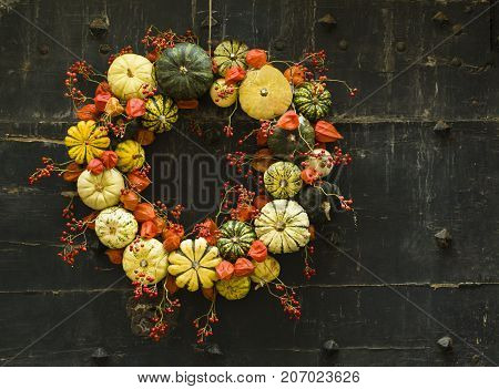 Handmade wreath of small pumpkins and zucchini on a vintage door Halloween pumpkins