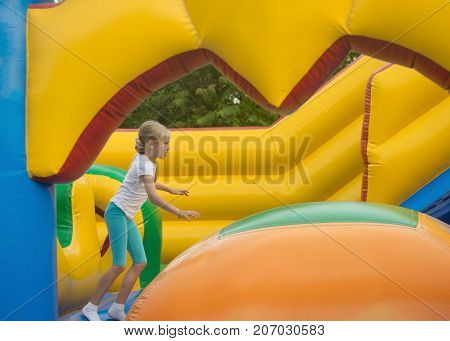 Little girl fun fun on an inflatable trampoline. The concept of a happy childhood.