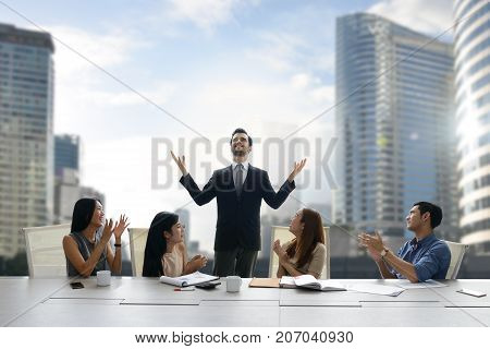 Colleagues applauding proud businessman in a team meeting
