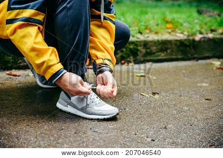 Running and sport concept.Sportsman hands tying shoelaces. autumn rainy day