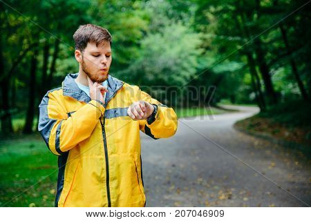 man measuring his pulse while running in autumn park