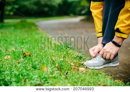 Running and sport concept.Sportsman hands tying shoelaces. autumn rainy day
