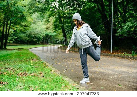 woman stretching in city park in autumn day