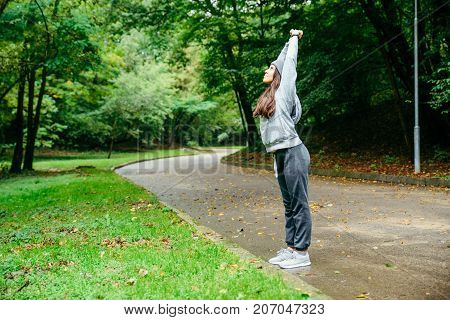 woman stretching in city park in autumn day