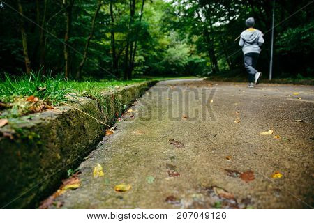 man runnin in autumn park with music in rainy weather