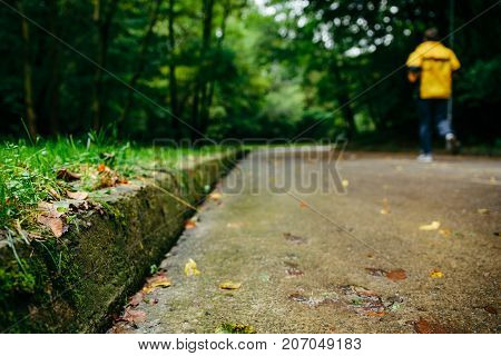 man runnin in autumn park with music in rainy weather
