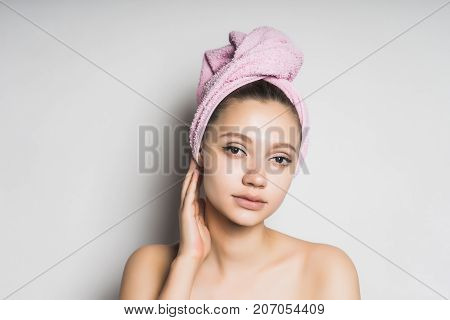 girl after shower with a pink towel on her head tiredly looks at the camera