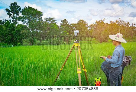 UBONRATCHATHANI THAILAND-SEPTEMBER 26 2017 : Asian smart engineer or surveyor is working on controller screen for surveying land in rice field. GPS surveying instrument.