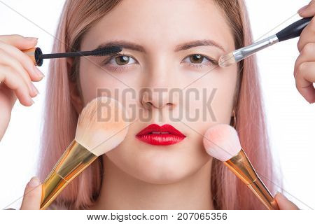 Closeup portrait of young beautiful woman with makeup brush around face. Isolated on white