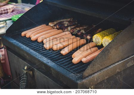Fresh Sausage And Hot Dogs Grilling Outdoors On A Gas Barbecue Grill.