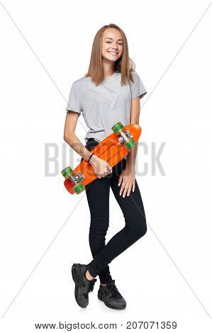 Teen girl in full length standing holding skate board smiling at camera, isolated on white background