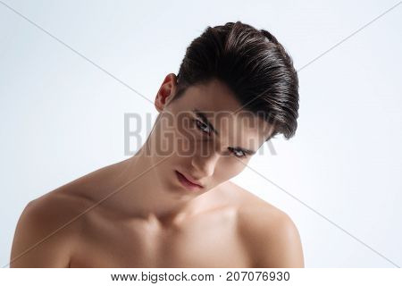Naked model. Attractive male model bowing head and demonstrating his naked body while posing on camera
