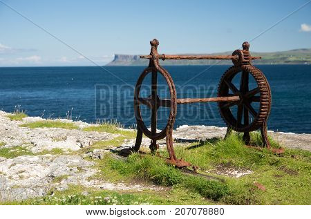 Old corroded iron winder with cogwheel, next to the sea, irish coast