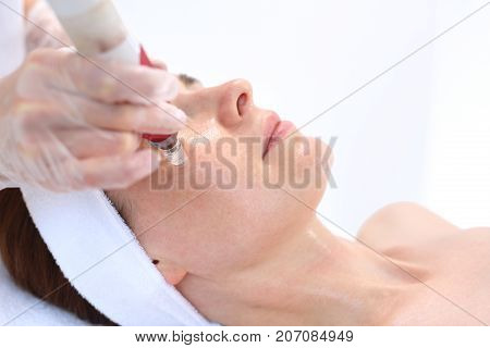 Needle mesotherapy, Beautician performs a needle mesotherapy treatment on a woman's face