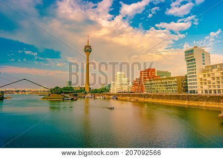 Looking at Media Harbor at Rhine-River in Dusseldorf in Germany. Media Harbor with Rhine-Tower and famous buildings in gentle sunset light with their reflection in the water. Beautiful and colorful cityscape of the german city
