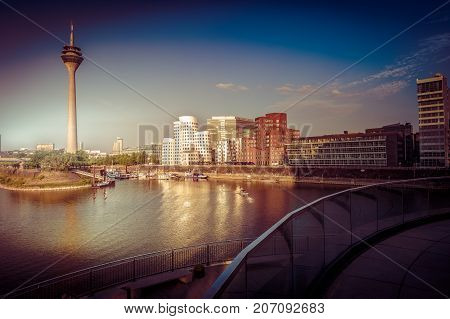 Looking at Media Harbor at Rhine-River in Dusseldorf in Germany. Media Harbor with Rhine-Tower and famous buildings in gentle sunset light with their reflection in the water. Beautiful and colorful cityscape of the german city