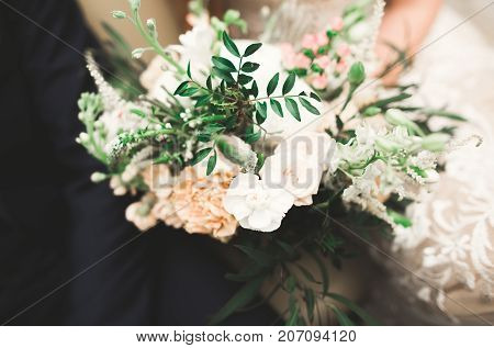 Beauty wedding bouquet with different flowers in hands.