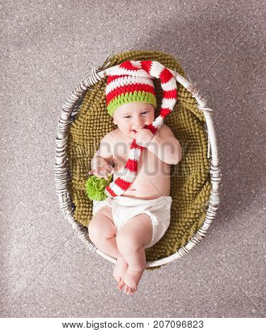 Adorable baby in Christmas gnome hat  lying in the basket. Newborn photography
