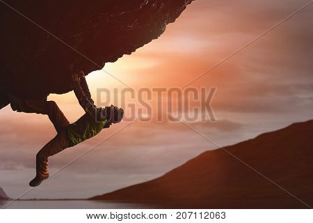 male rock climber. rock climber climbs on a black rocky wall on the ocean bank in Iceland, Kirkjufjara beach. man makes hard move without rope.