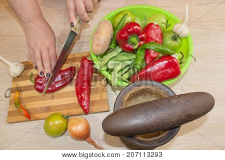 Chef cuts the vegetables into a meal. Preparing dishes. A woman uses a knife and cooks. Woman's hands cutting bell pepper behind fresh vegetables