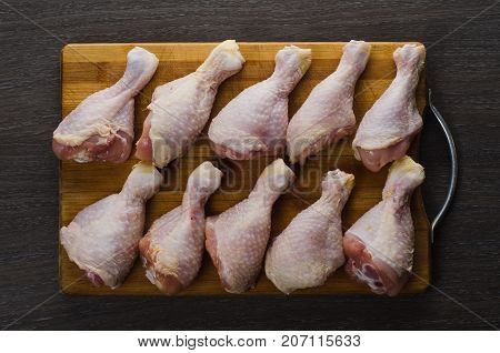 Fresh raw chicken legs arrangement on a kitchen cutting board