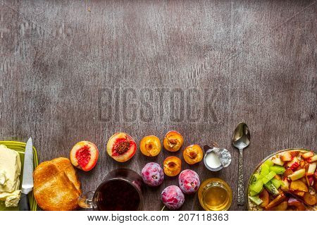 Oatmeal with plums and peach, toast with butter and honey on a wooden table. A cup of black tea. The concept of a healthy breakfast. Top view. Copy space. Still life. Flat lay