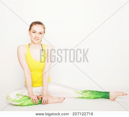 lifestyle, sport  and people concept: young woman in yoga pose sitting on a floo