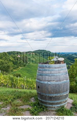 Jars with grapes and candle on wooden barrel near vineyard on south Styrian wine route in Austria