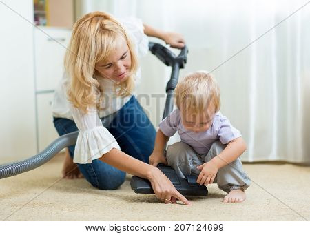 family mother and child boy cleaning the room with vacuum-cleaner - housework