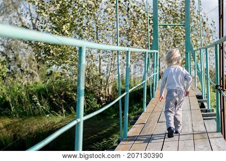 Old wooden pendant bridge with a child, The Urals village, Russia