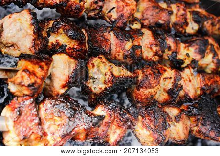 closeup of some meat skewers being grilled in a barbecue. side view
