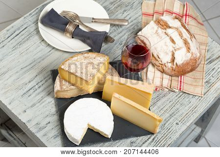 Different french cheeses with a glass of red wine