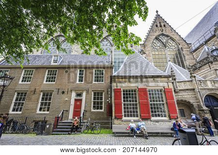 AMSTERDAM NETHERLANDS - JUNE 21 2016: Tourists in front of the Old Church (Oude Kerk) in a cloudy day. Amsterdam Netherlands.