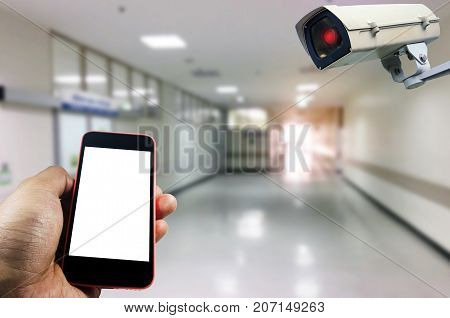 hand using smart phone monitoring and CCTV security indoor camera system operating in hospital background internet medical network connection surveillance security and safety technology concept
