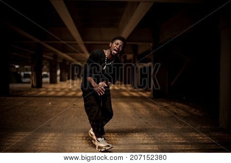 Emotional full length portrait of afro american guy with open mouth in the half squat dressed in trendy black clothes