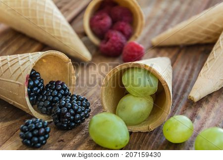 Ice cream cone with grape, blueberry, raspberry on wooden background