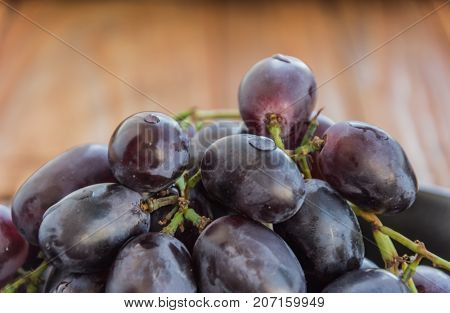 Fresh tasty grape with branch on wooden background