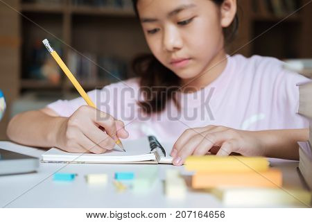 Girl Reading And Writing In Library Of School.