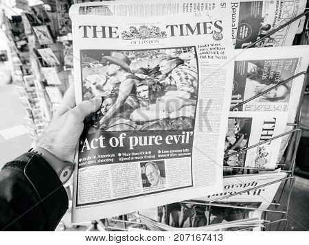 PARIS FRANCE - OCT 3 2017: Man buying The Times newspaper with socking title and photo at press kiosk about the 2017 Las Vegas Strip shooting in United States with about 60 fatalities and 527 injuries