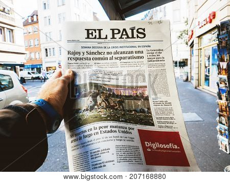PARIS FRANCE - OCT 3 2017: Man buying Spanish El Pais newspaper with socking title and photo at press kiosk about the 2017 Las Vegas Strip shooting in United States with about 60 fatalities and 527 injuries