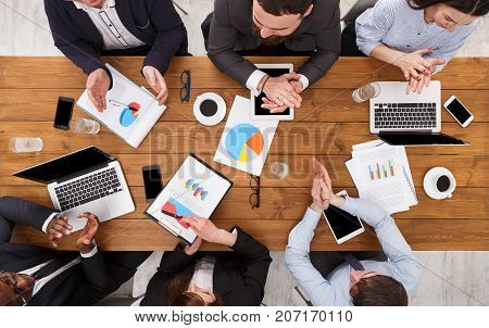 Multiethnic business team in office. Employees clapping hands cheering successful reporter top view of wooden table