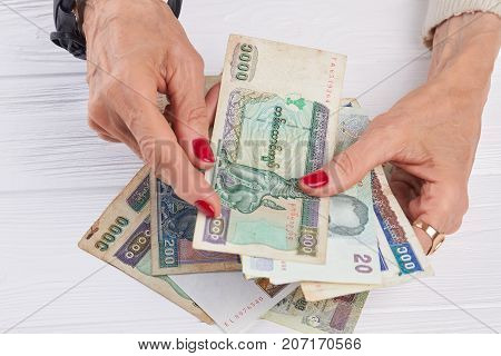 Burma banknotes in caucasian woman hands. Female manicured hands holding national currency of Myanmar close up. Manicured hands and kyat money.