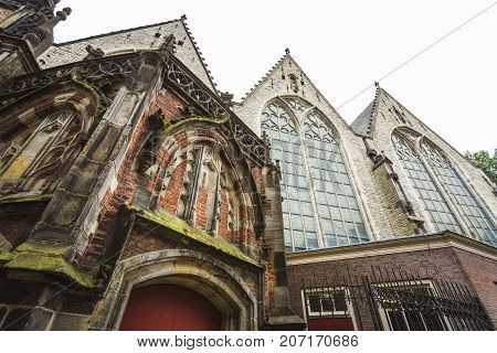 Point of view of the Old Church (Oude Kerk) located in the Red Light District Amsterdam in a cloudy day.