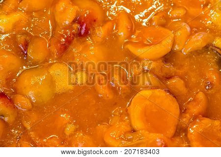 Apricot jam cooked in a bowl and jammed with a wooden spoon