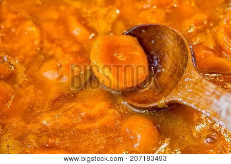 Apricot jam cooked in a bowl and jammed with a wooden spoon