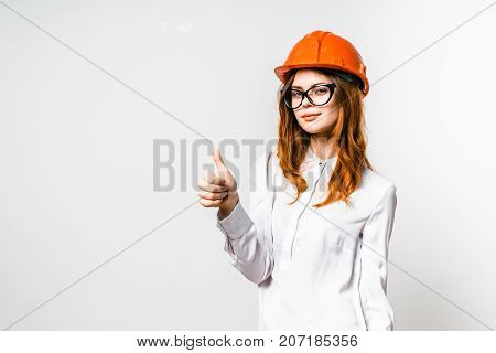 young girl in orange construction helmet showing thumb