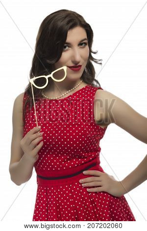 Youth Lifestyle Concept. Portrait of Sensual Alluring Caucasian Female Holding Yellow Artistic Spectacles In Front Of Face. Posing In Red Polka Dot Dress Against Pure White.Vertical Image Composition